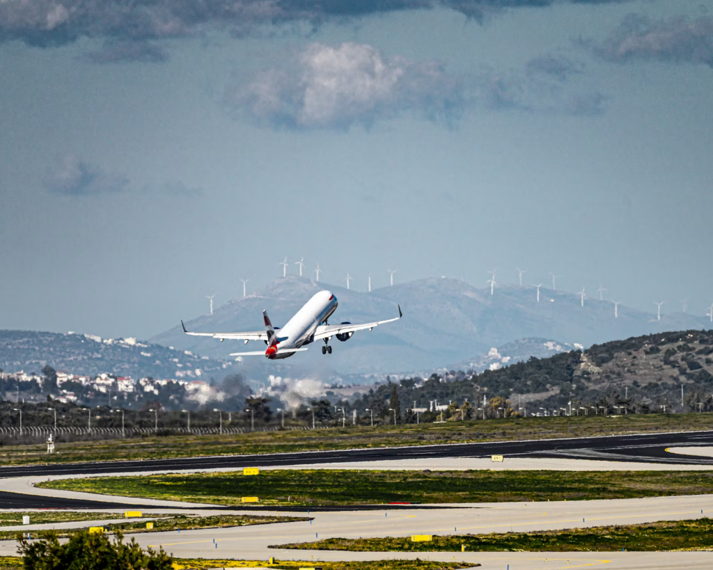 Aircraft taking off near wind turbines, symbolizing Europe’s focus on sustainable aviation and SAF targets by 2050.