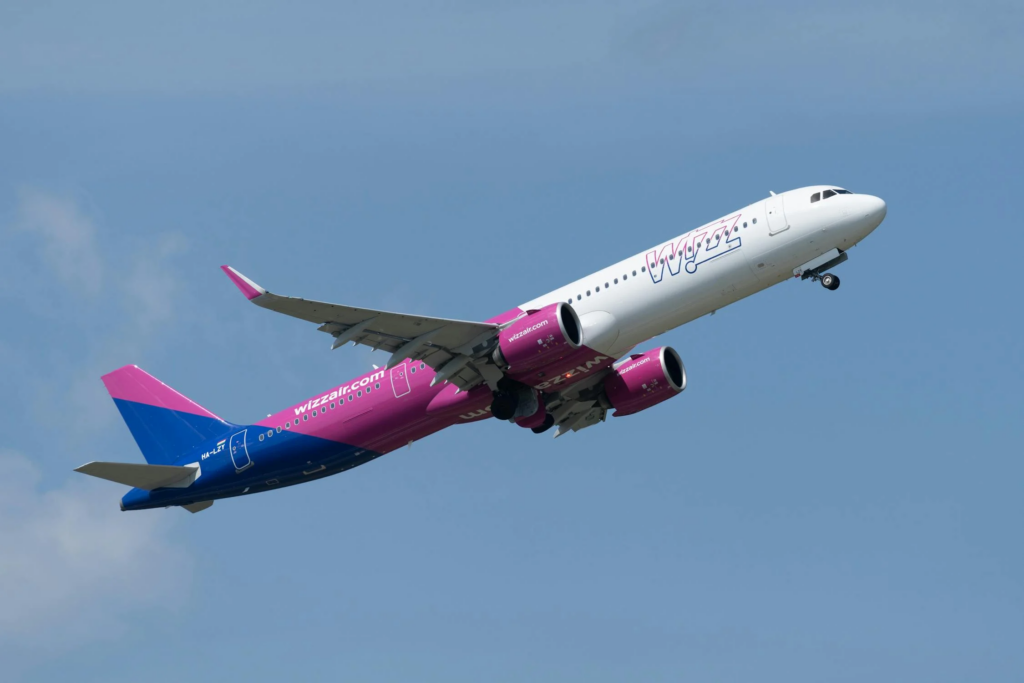 Wizz Air Airbus A321neo climbing after takeoff against a clear blue sky