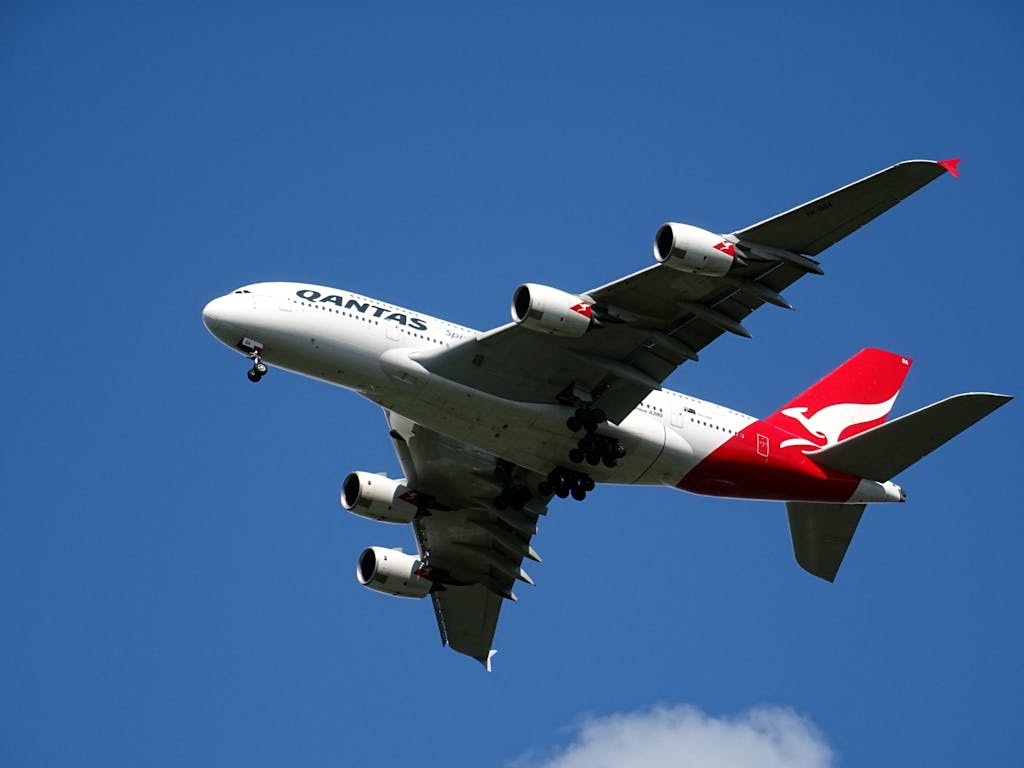 A Qantas Airbus A380 soaring against a bright blue sky, showcasing aviation marvel.
