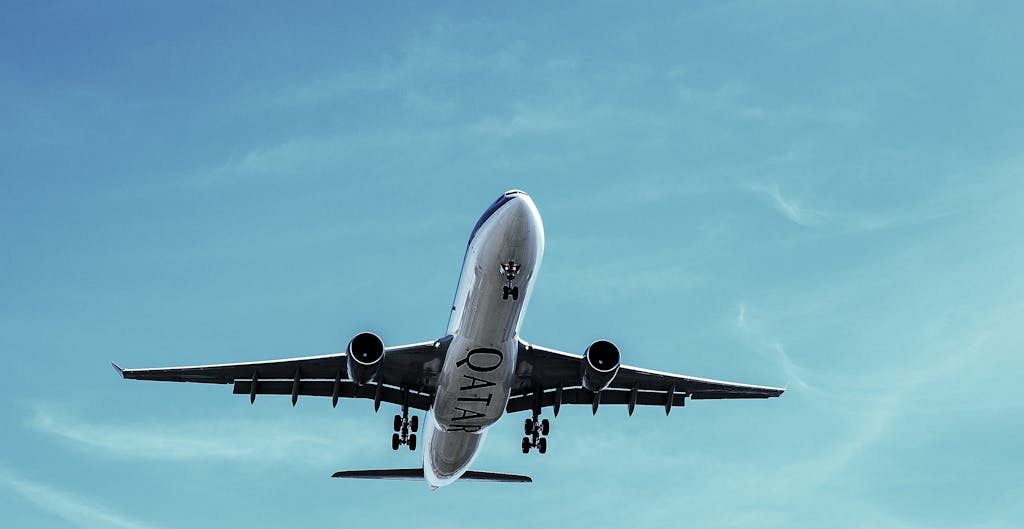 A Qatar Airways commercial airplane takes off into a clear blue sky, showcasing transportation at its finest.